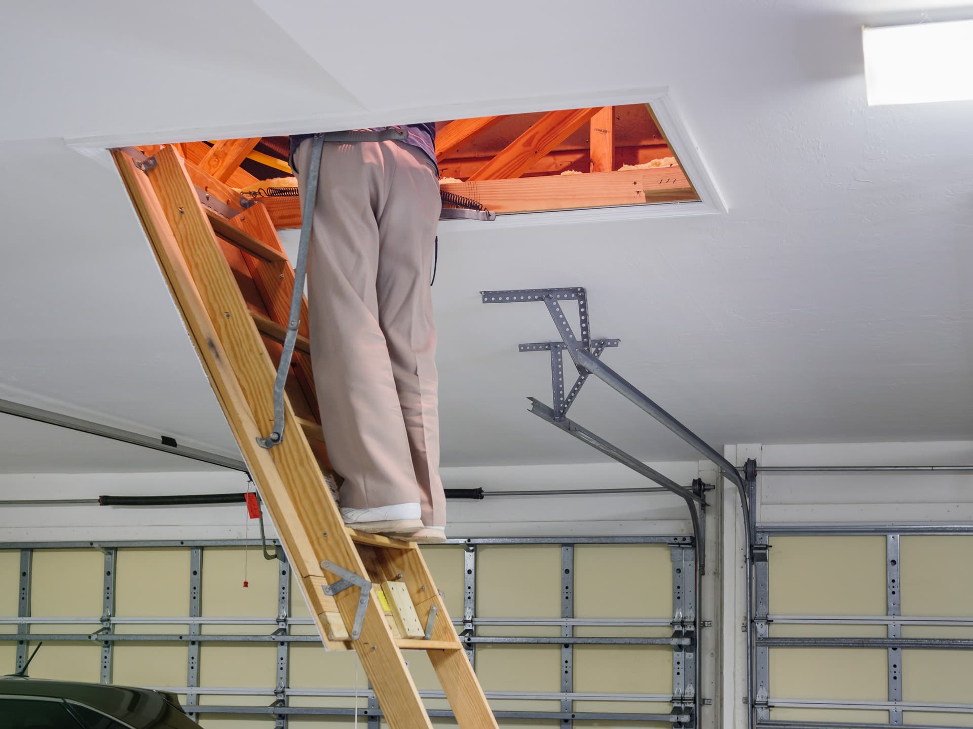 Technician climbing an attic access ladder to inspect an enclosed space