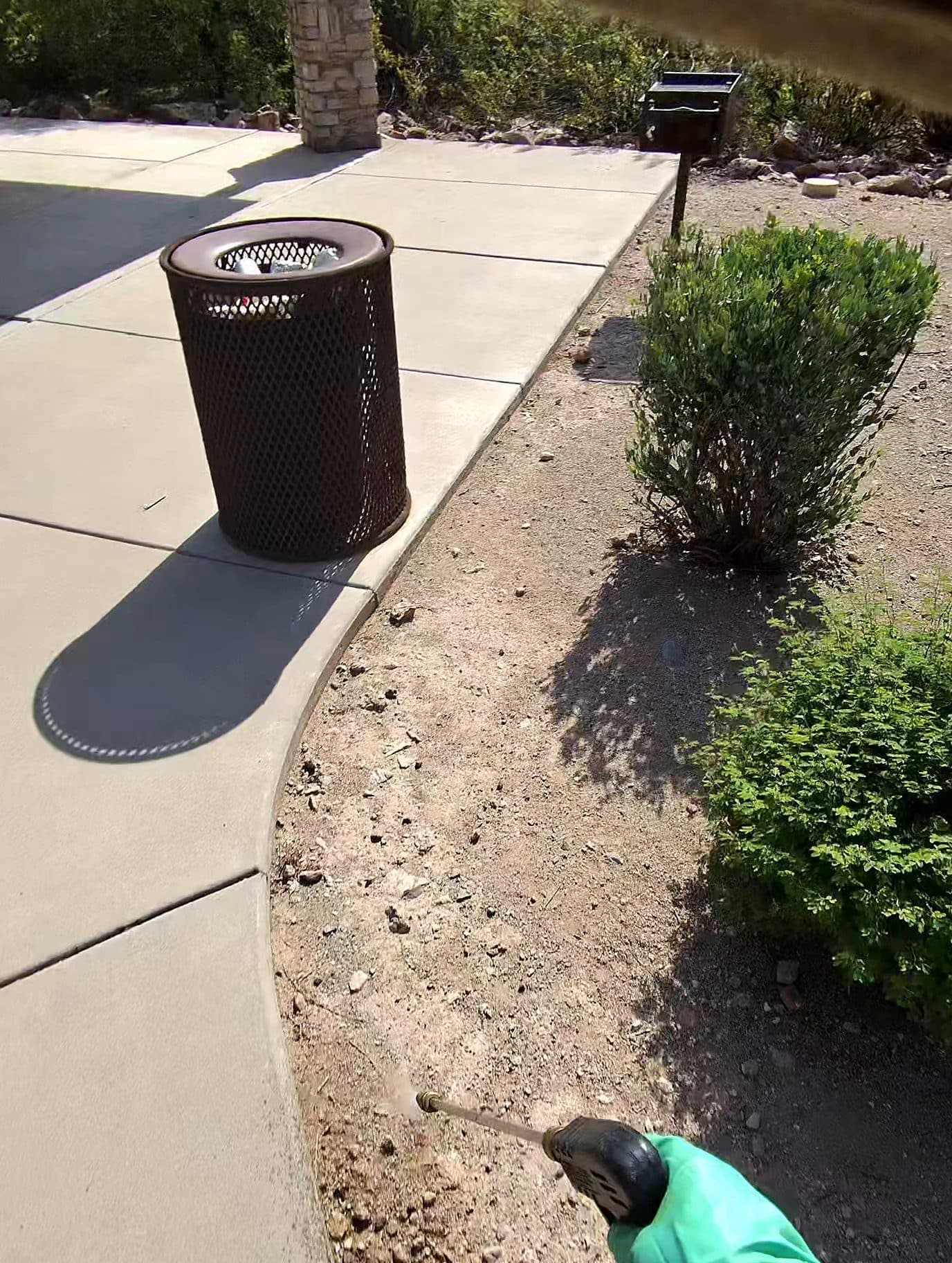 Technician spraying a sidewalk perimeter treatment at a Phoenix-area home