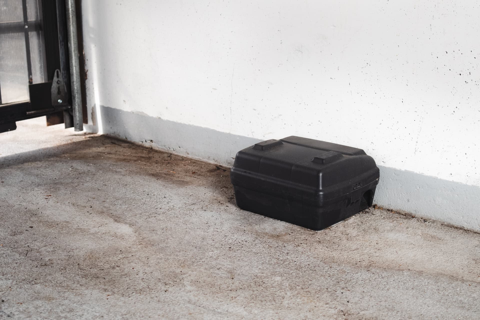 Commercial rodent bait station stationed along a building wall