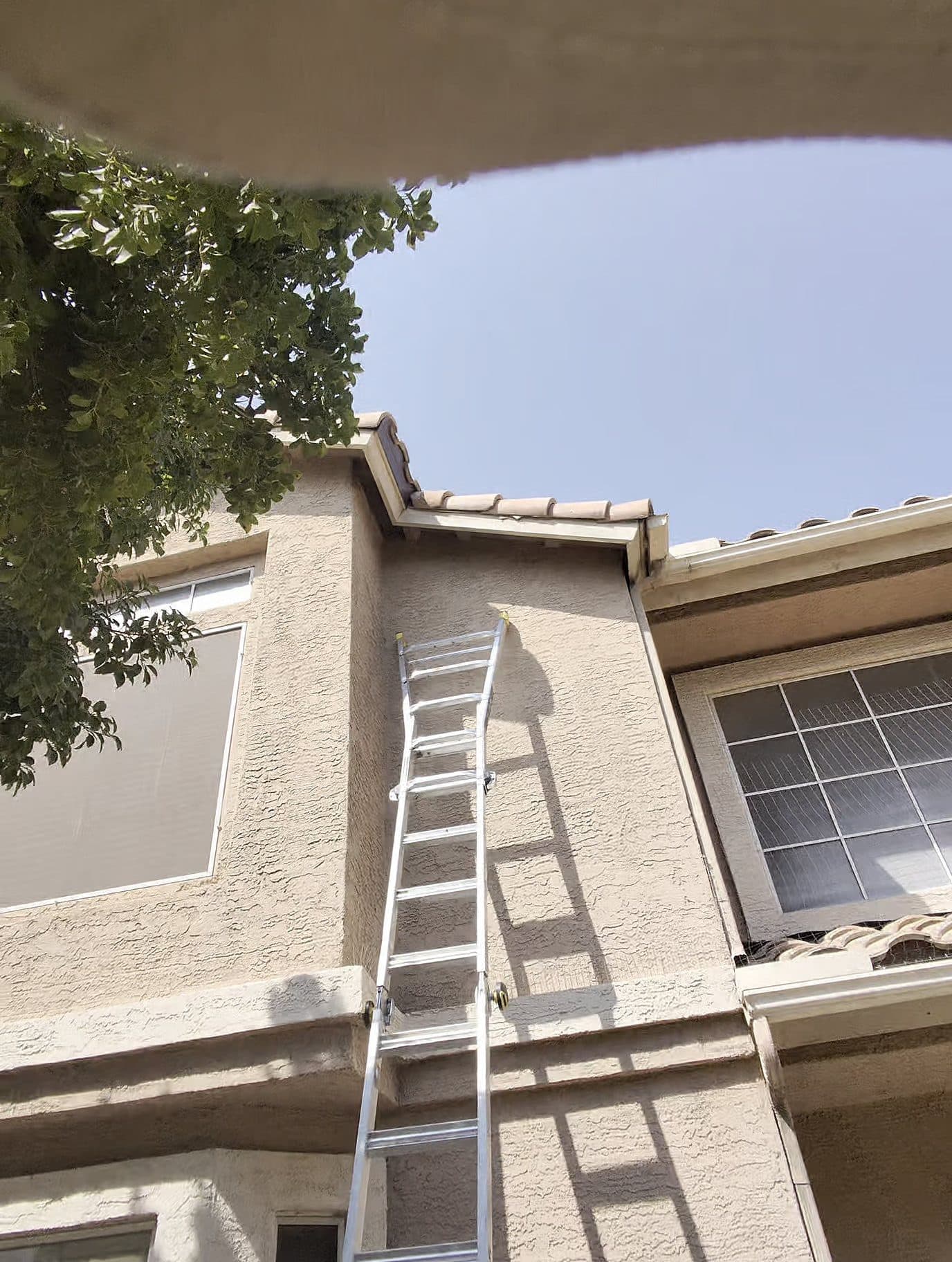 Ladder set against a two-story Phoenix home for roof access