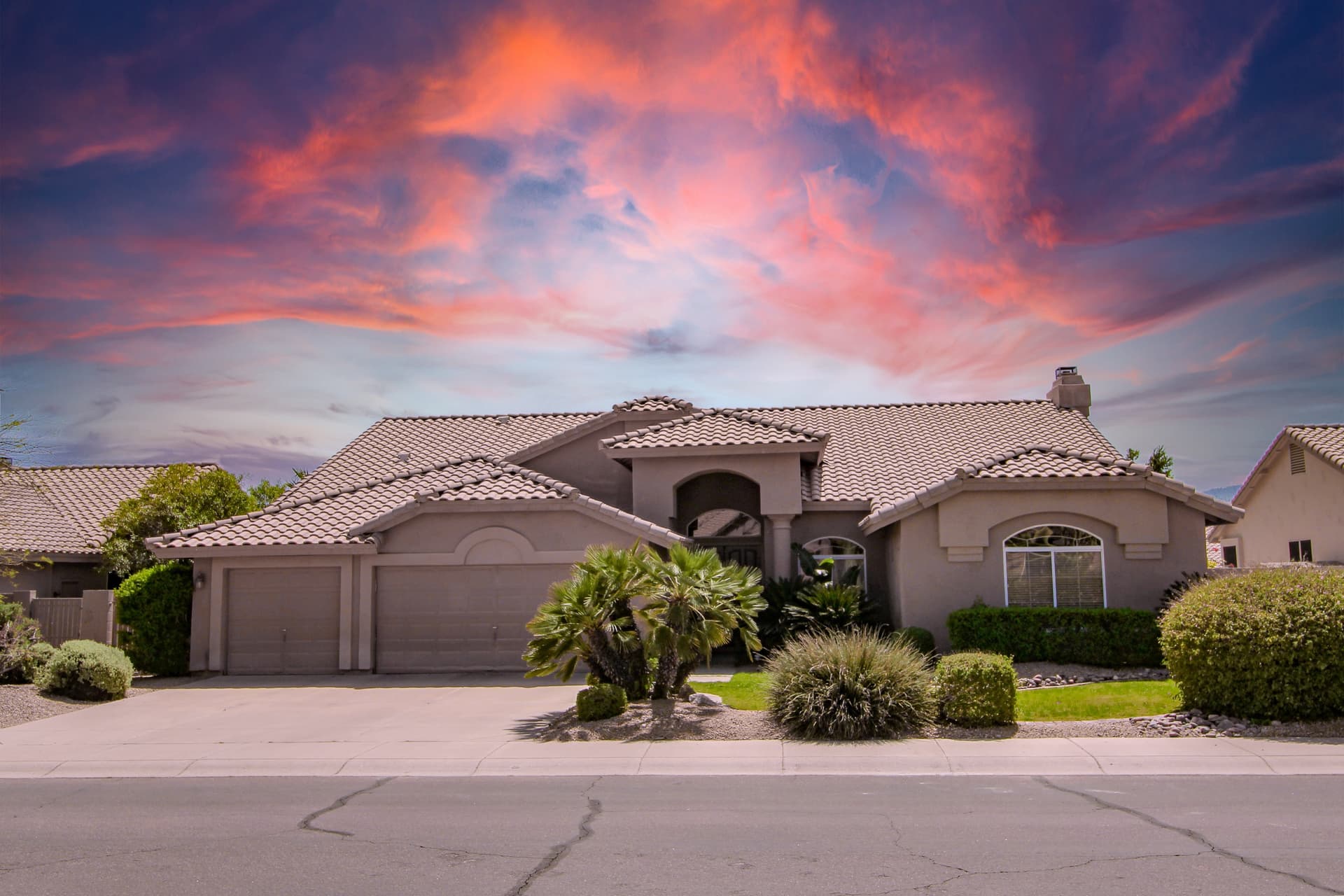 Phoenix tile-roof home with palms under a sunset sky